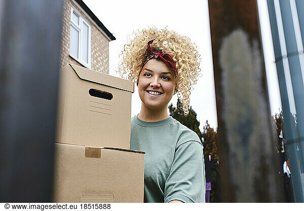Smiling young woman with curly hair delivering packages
