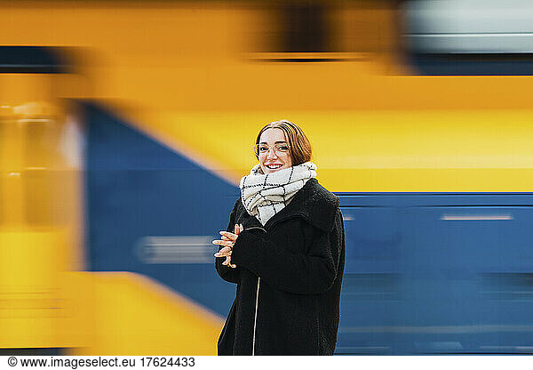 Smiling young woman with eyeglasses by subway train