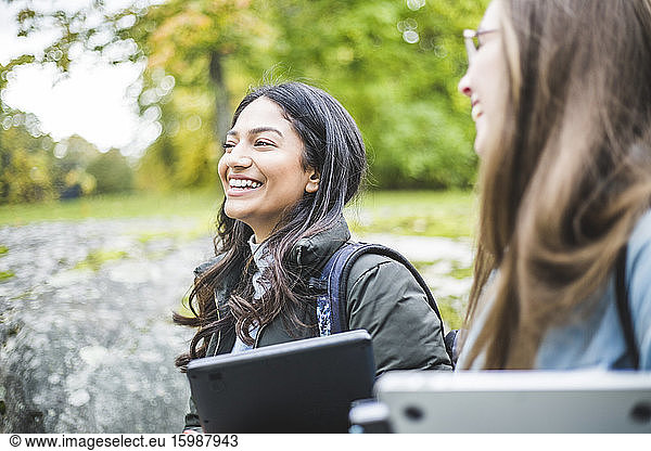 Smiling young woman with female friend in university campus