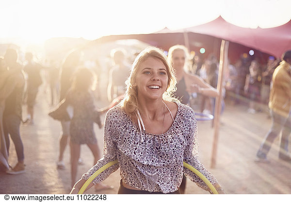 Smiling young woman with plastic hoop at music festival