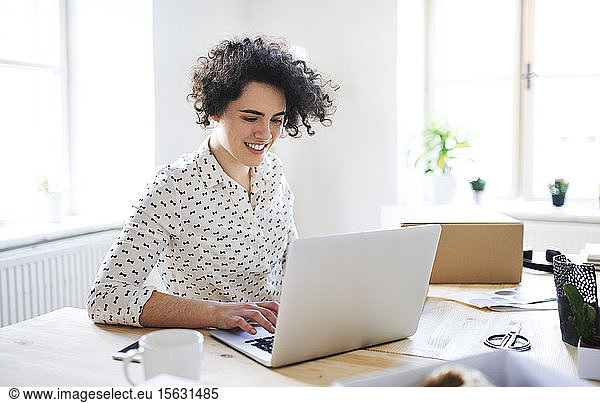 Smiling young woman working on laptop at desk