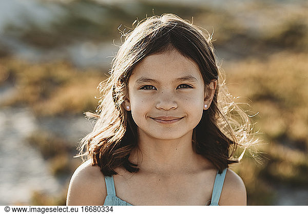 Smiling 8 yr old girl with sunlight playing through her dark hair