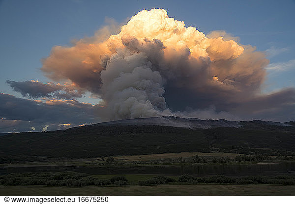 Smoke emitting from wildfire on mountain against sky