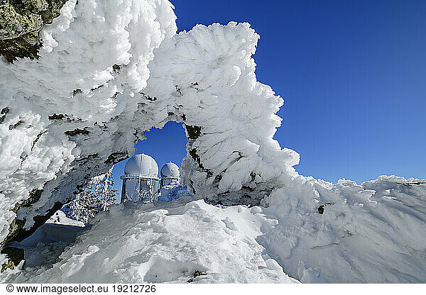 Snow covered rock formation on mountain with blue sky in background