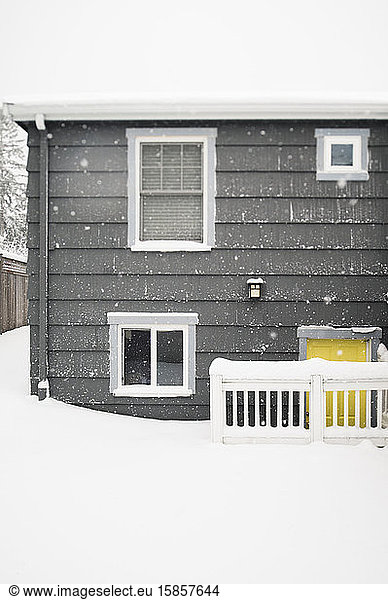 Snow Falling on Building Exterior with Yellow Door