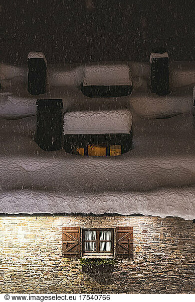 Snow falling outside brick house at night