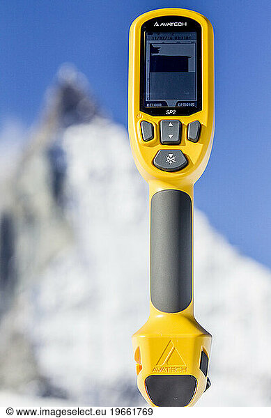 Snow profile measuring device with mountain peak in background