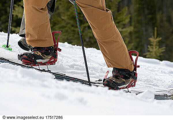 Snowboarder in brown pants skinning uphill