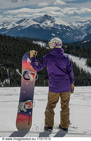 Snowboarder in Purple gazing at snow covered mountains in Colorado