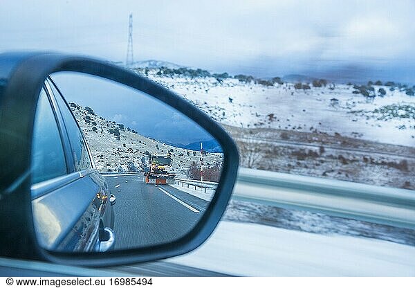 Snowplow working in the highway. Rear view mirror.