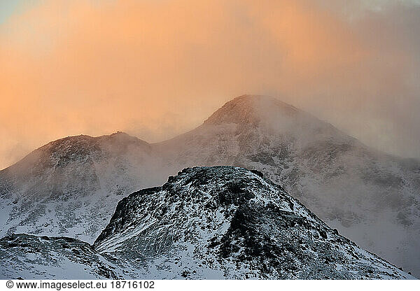 Snowy mountain ridge and clouds during sunset