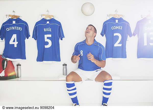 Soccer player bouncing ball in locker room