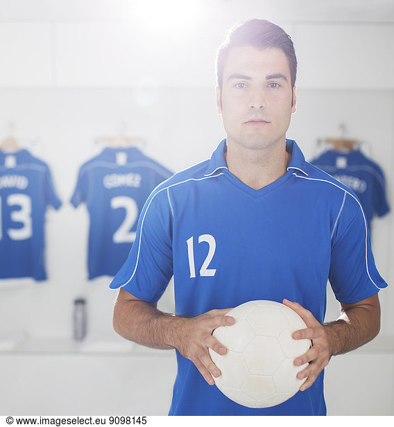 Soccer player holding ball in locker room