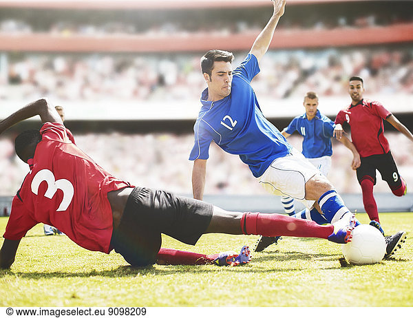 Soccer players kicking ball on field