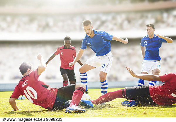 Soccer players sliding on field