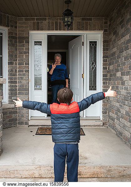 Social distance visit between young boy and his grandmother at home.
