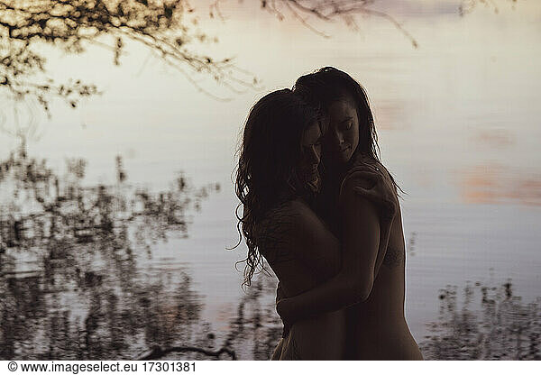 soft embrace of lesbian queer couple hugging by romantic lake