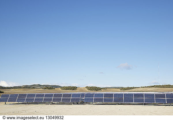 Solar panels on landscape against blue sky