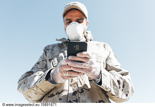 Soldat mit Gesichtsmaske bei Notfalleinsätzen  mit Smartphone