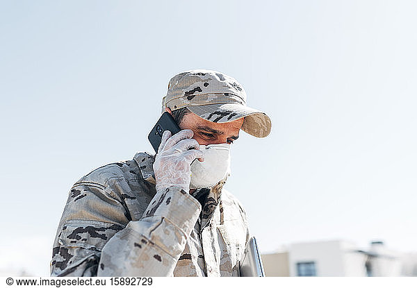 Soldat mit Gesichtsmaske bei Notfalleinsätzen  mit Smartphone