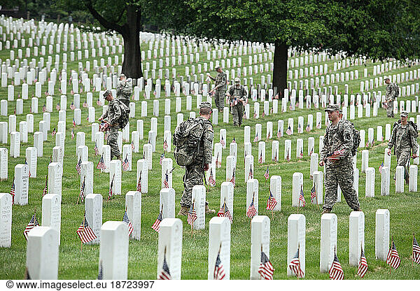 Soldiers place flags on graves at Arlington National Cemetery.
