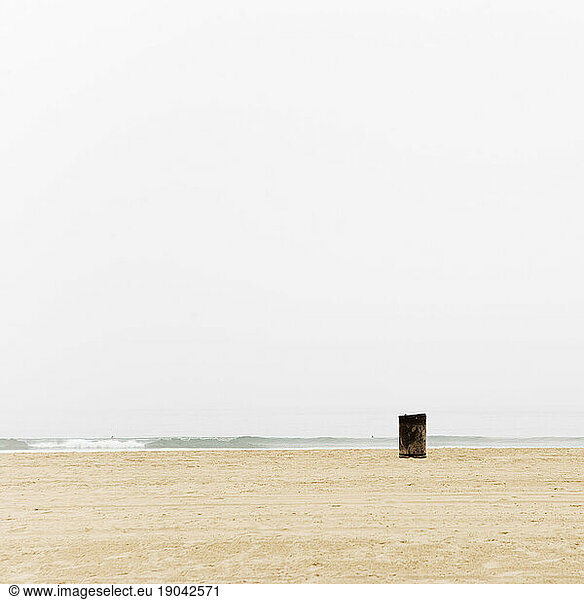 Solitary garbage can on the beach.