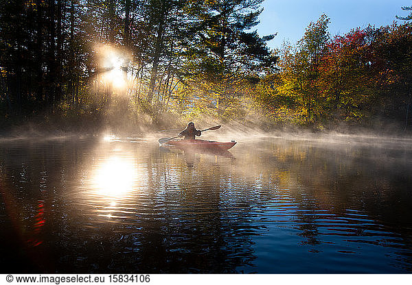 Solo paddling on a misty pond at sunrise.