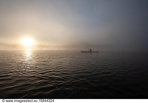 Solo paddling on a misty pond at sunrise.