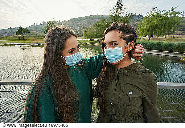 some beautiful women posing with masks looking at each other. the othe