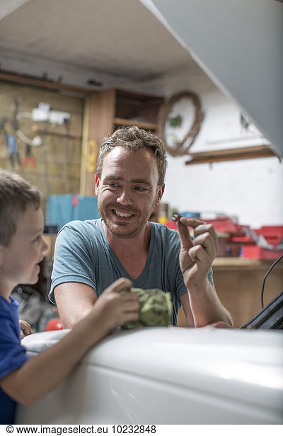 Son helping father in home garage working on car