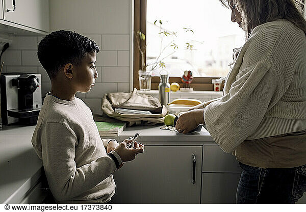 Son looking at mother while standing in kitchen