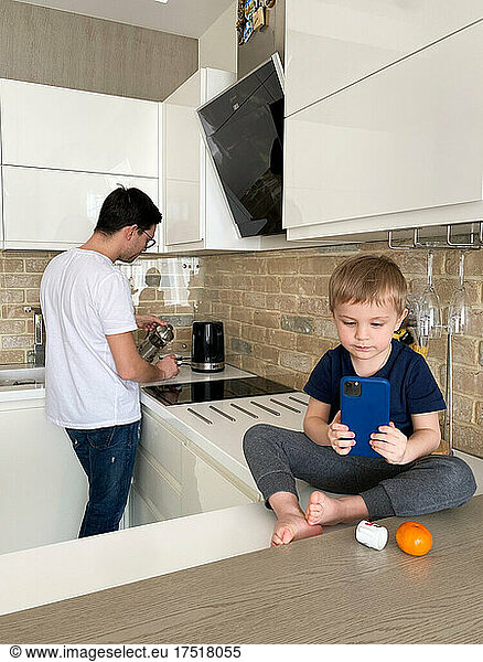 son making photos while father making tea