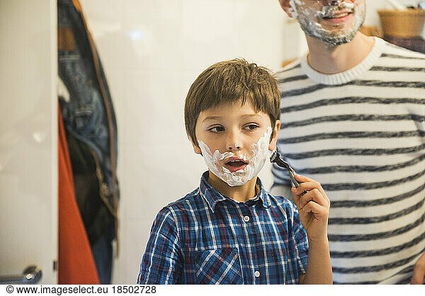 Son shaving in bathroom while father watches  Munich  Germany