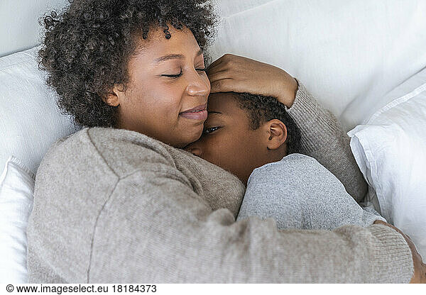 Son sleeping in mother's arms at home