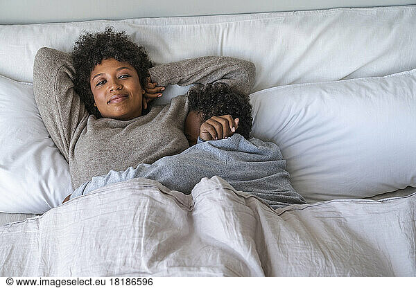 Son sleeping with mom on bed at home