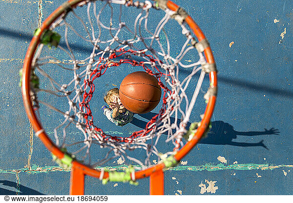Son throwing basketball standing under hoop