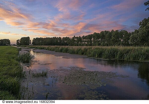 Sonnenuntergang über einem Kanal im niederländischen Naturschutzgebiet Kraaiebos nahe dem Dorf Sliedrecht in der Region Alblasserwaard.