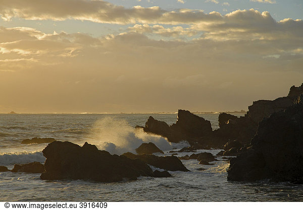 Sonnenuntergang hinter den Wellen und den Klippen am Cape Palliser an der Cook Strait  Cookstraße  an der Südspitze der Nordinsel  Neuseeland