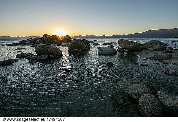Sonnenuntergang mit Sonnenstern  Runde Steine im Wasser  Ufer am See Lake Tahoe  Sand Harbor State Park  Ufer  Kalifornien  USA  Nordamerika