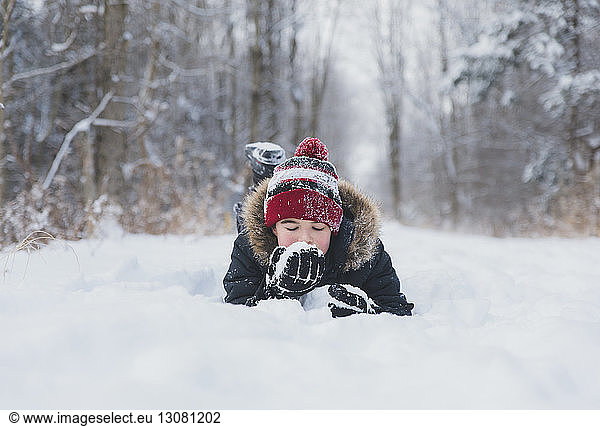 Sorgenfreier Junge liegt auf verschneitem Feld