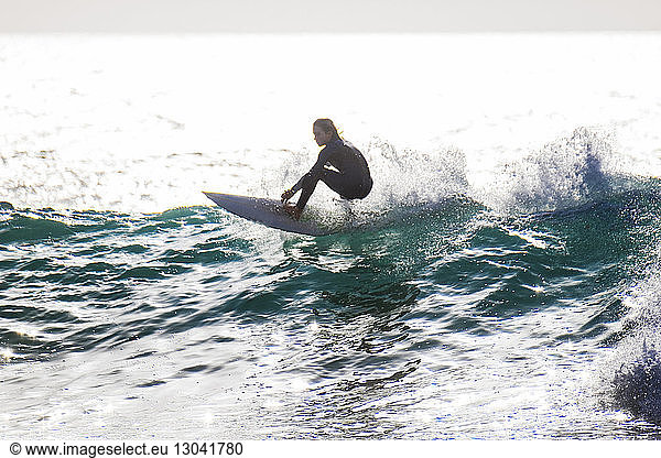 Sorgloser Teenager Junge surft im Meer