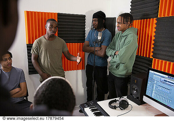 Sound engineer and rappers discussing in recording studio