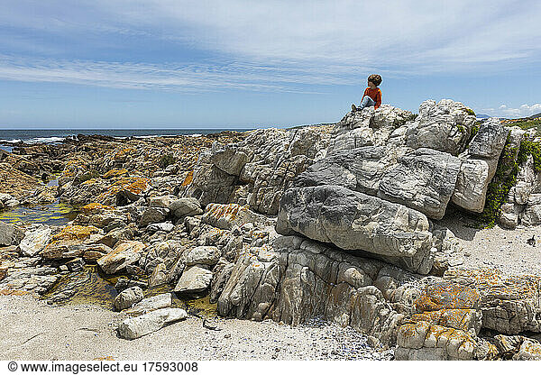 South Africa Hermanus Boy (8-9) exploring rocks on Sandbaai Beach
