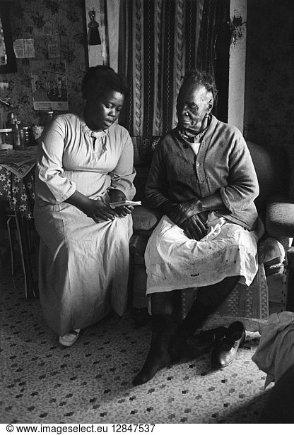 SOUTH CAROLINA: POVERTY. Americorps Vista volunteer  Rachel Polite (left)  reads to her elderly neighbor in Frogmore  South Carolina. Photograph  1973.