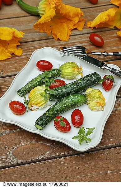 Southern German cuisine  stuffed courgette flowers sautéed on plate  cream cheese  cocktail tomatoes  cherry tomatoes  vegetarian  healthy cuisine  vegetables  cutlery  knife  fork  wooden plate  Germany  Europe