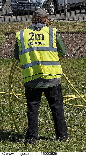 Southsea  Portsmouth  England  A municipal key worker wearing a reflective jack with the words  Keep 2m Distance during the Covid-19 outbreak.