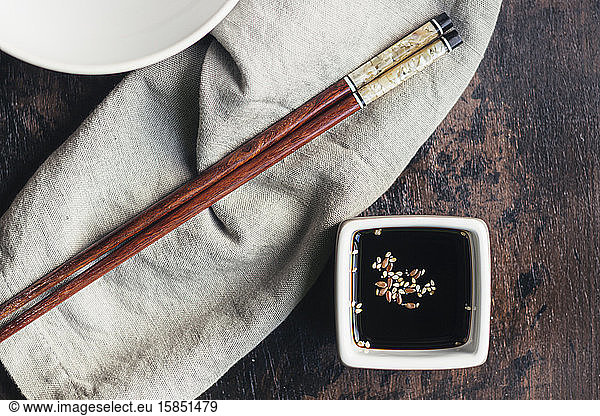 Soy sauce and sesame in a vessel and bamboo chopsticks