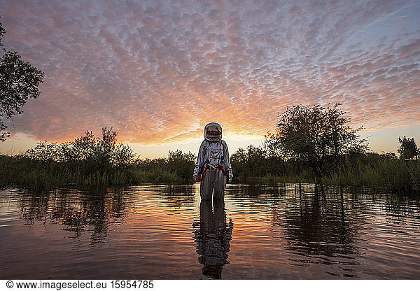 Spacewoman standing in water at sunset