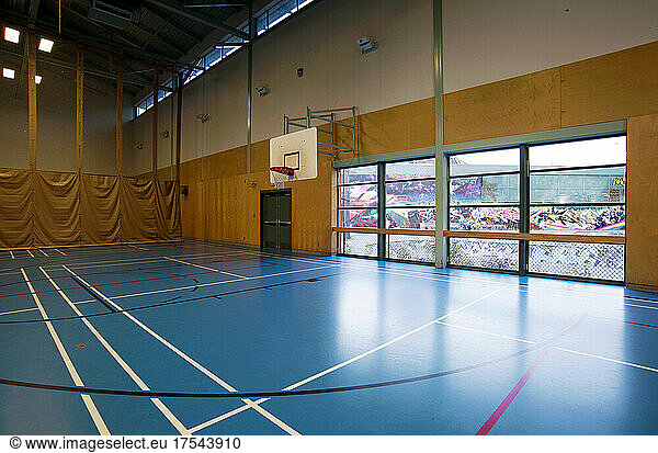 Spacious gymnasium with a basketball court floor markings  light and airy  glass doors