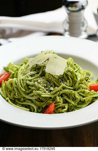 Spaghetti with pesto sauce and slices of parmesan cheese